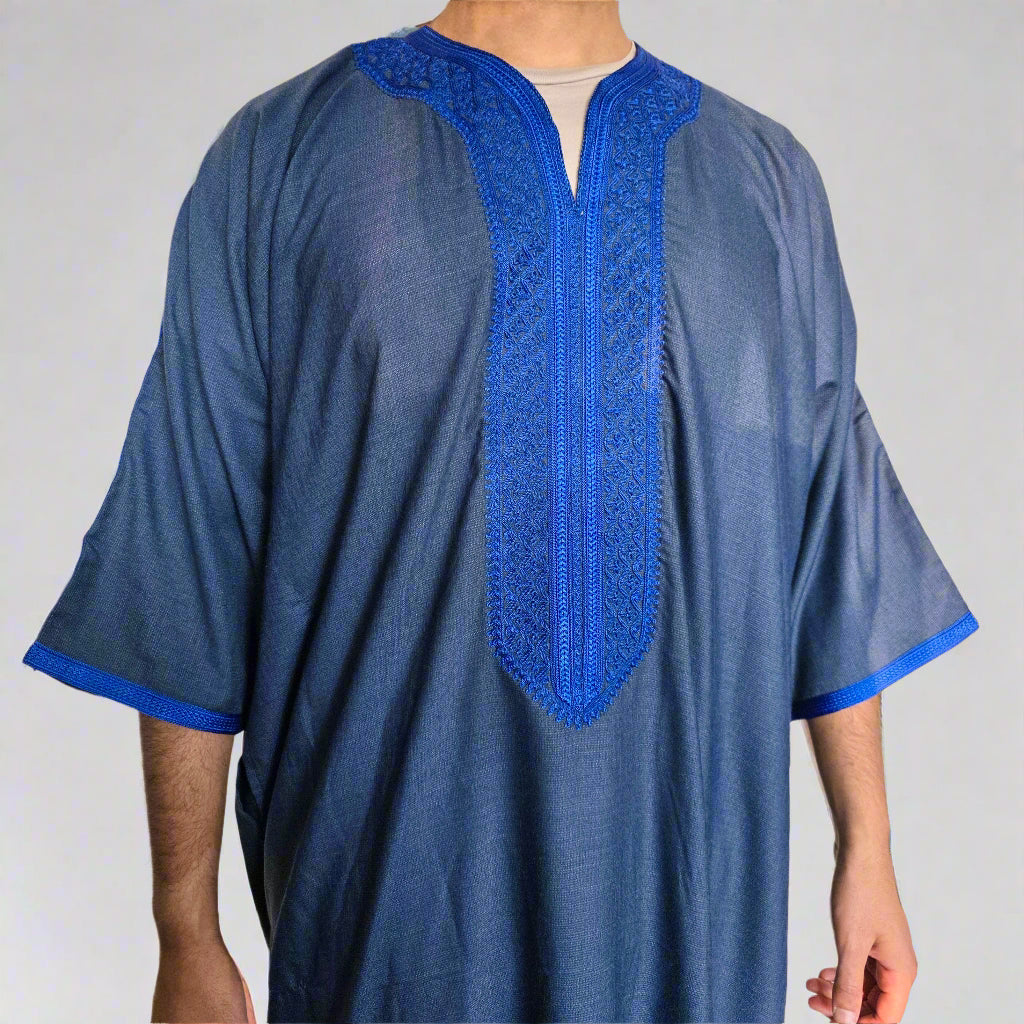 Blue embroidered traditional garment worn by a person against a neutral background