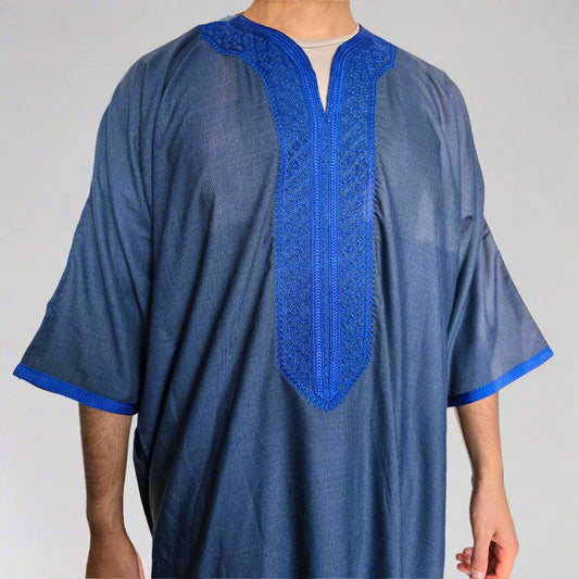 Blue embroidered traditional garment worn by a person against a neutral background