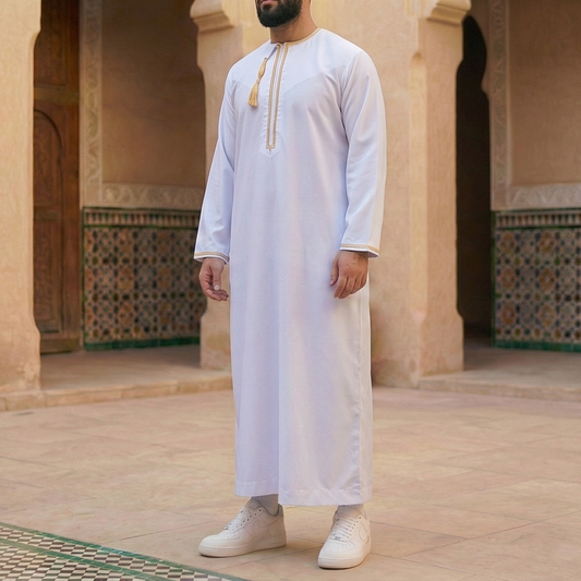 man wearing white and gold omani thobe with detachable tassel
